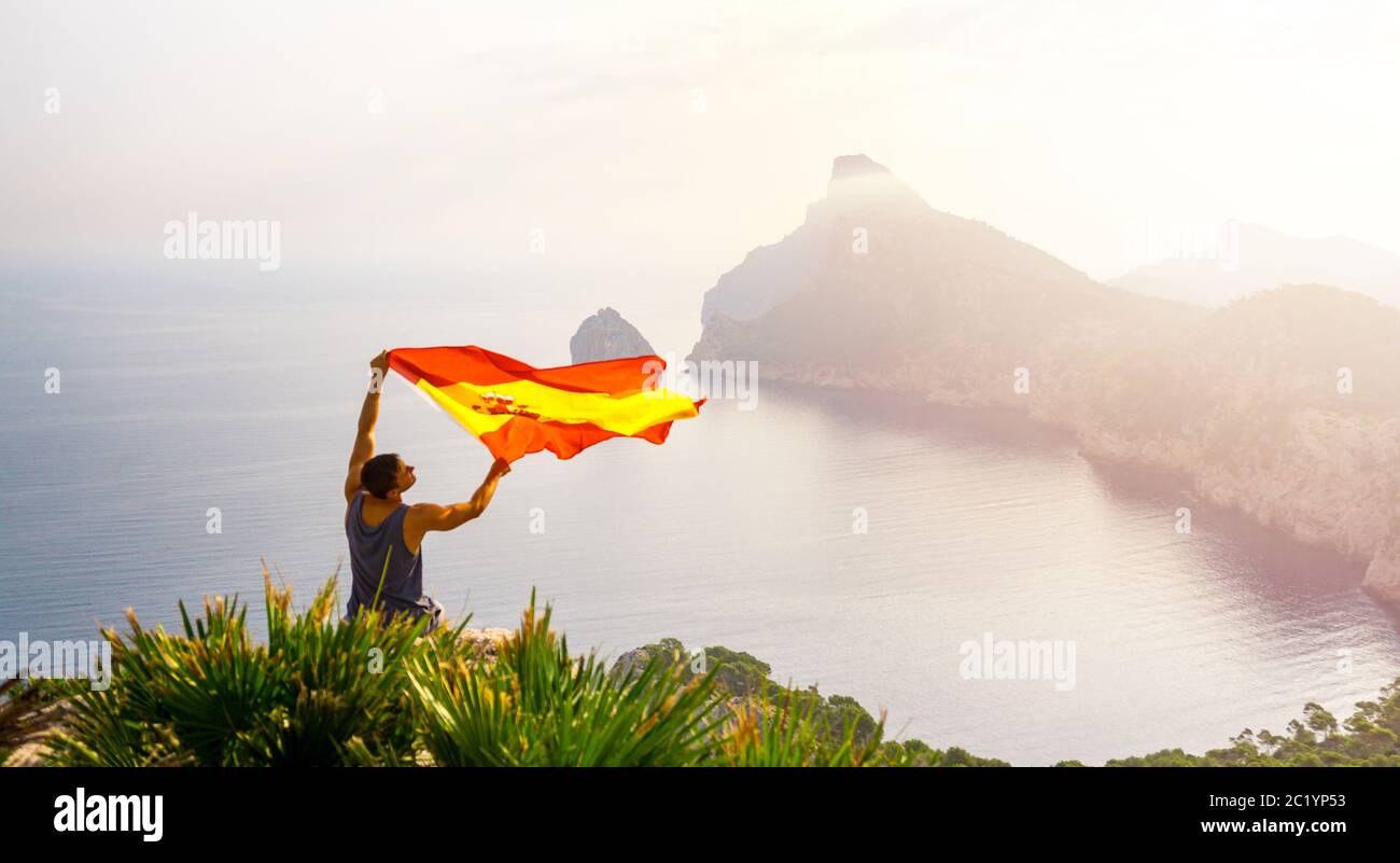 Happy man with spain flag during sunrise on dyllic coastline of Majorca ...