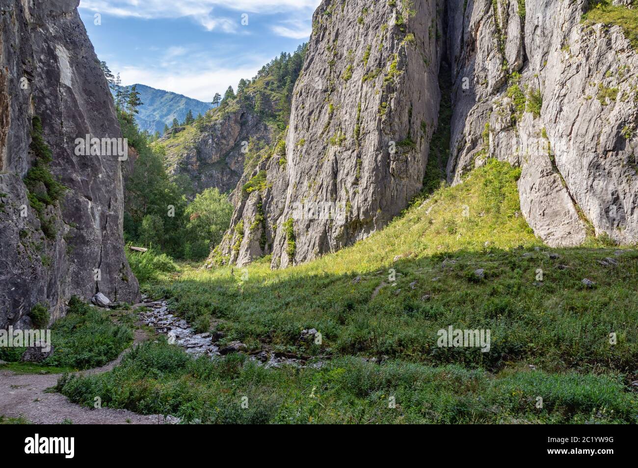 a small stream flows between the mountains and flows into the river Stock Photo