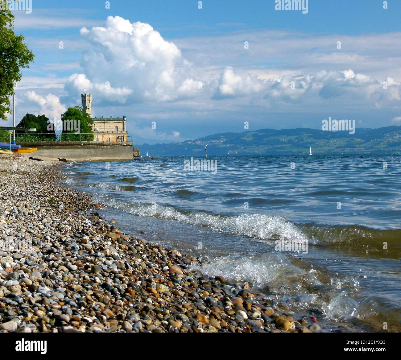 Lake with gravel beach and a water castle and great clouds in the background Stock Photo