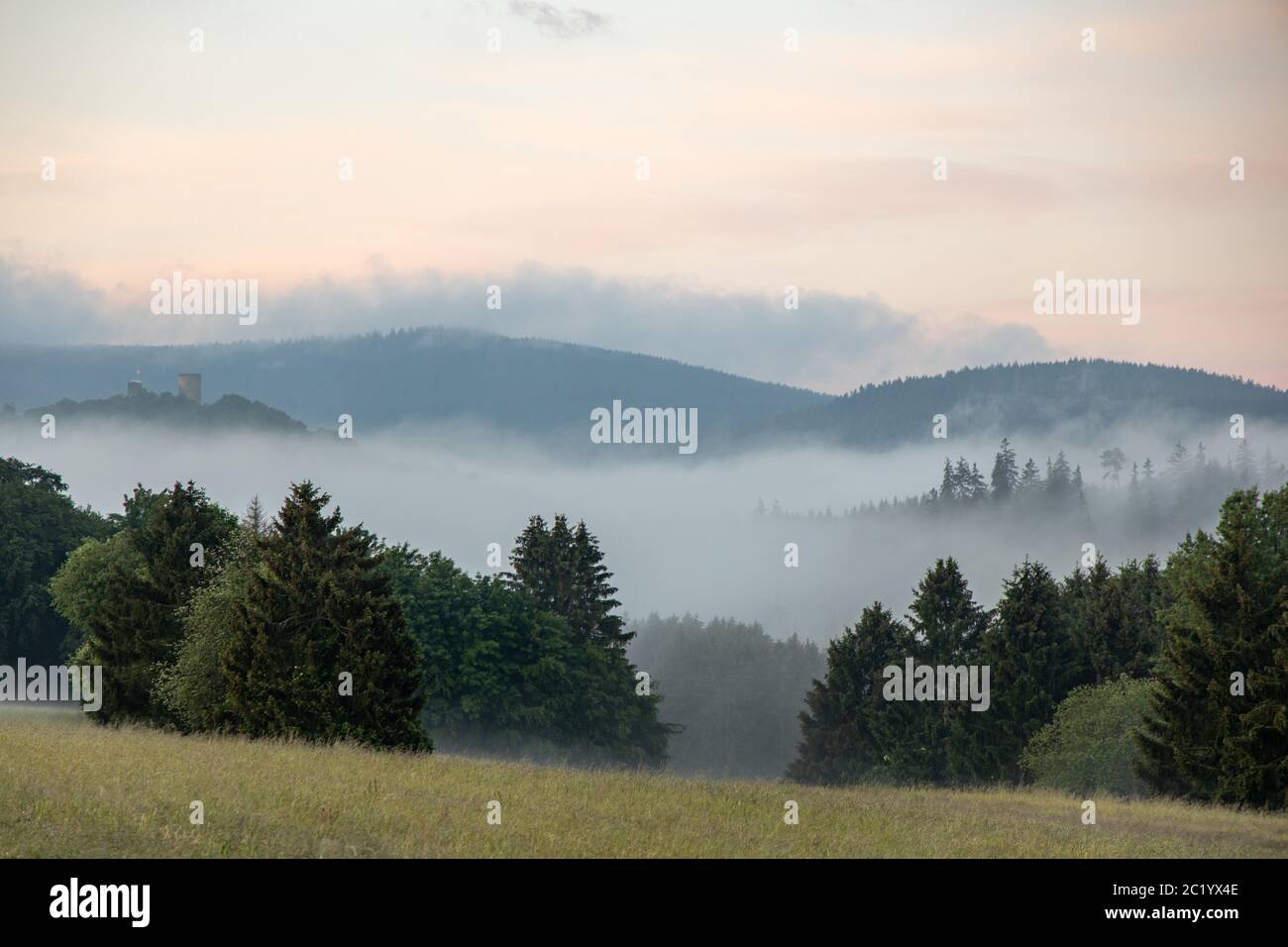 June 12th, 2020, Schwithten (Hessen): Fog lies in the early morning over the fields and the forest at Schwithten Seelenberg. (In the background the ruins of Reifenberg) | usage worldwide Stock Photo