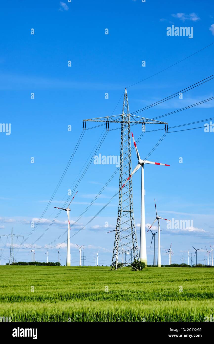 Overhead power lines and wind energy generators seen in Germany Stock Photo