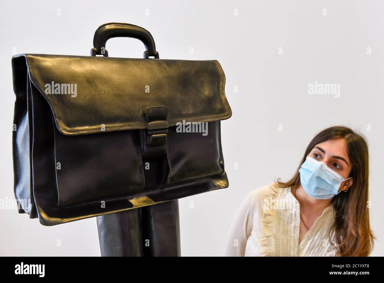 London, UK.  16 June 2020.  A staff member wearing a facemask views 'Direktor (Herrentasche) (Taschenskulpturen)', 2019, by Erwin Wurm on the opening day of a new exhibition 'Art Basel at Ely House' taking place at Galerie Thaddaeus Ropac in Mayfair.  The commercial gallery has implemented social distancing guidelines for visitors for its reopening after coronavirus pandemic lockdown restrictions were relaxed by the UK government.  The exhibition runs 16 June to 31 July 2020.  Credit: Stephen Chung / Alamy Live News Stock Photo