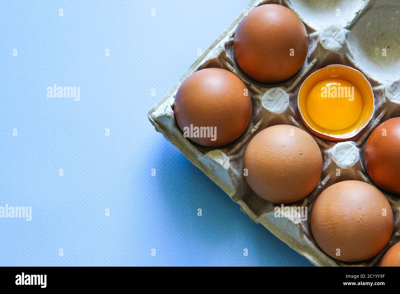 Brown eggs and egg yolk on the blue background. Top view. Flat lay