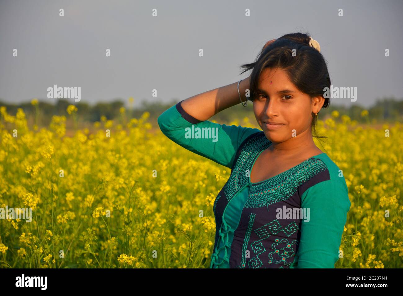 : An Indian teenage girls smiling and posing for photograph in a mustard field, selective focusing Stock Photo