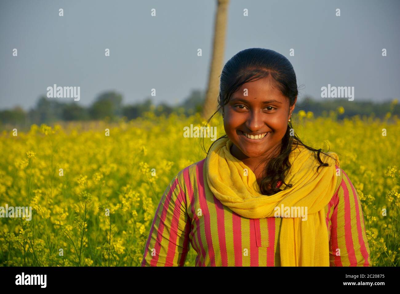 : An Indian teenage girls smiling and posing for photograph in a mustard field, selective focusing Stock Photo