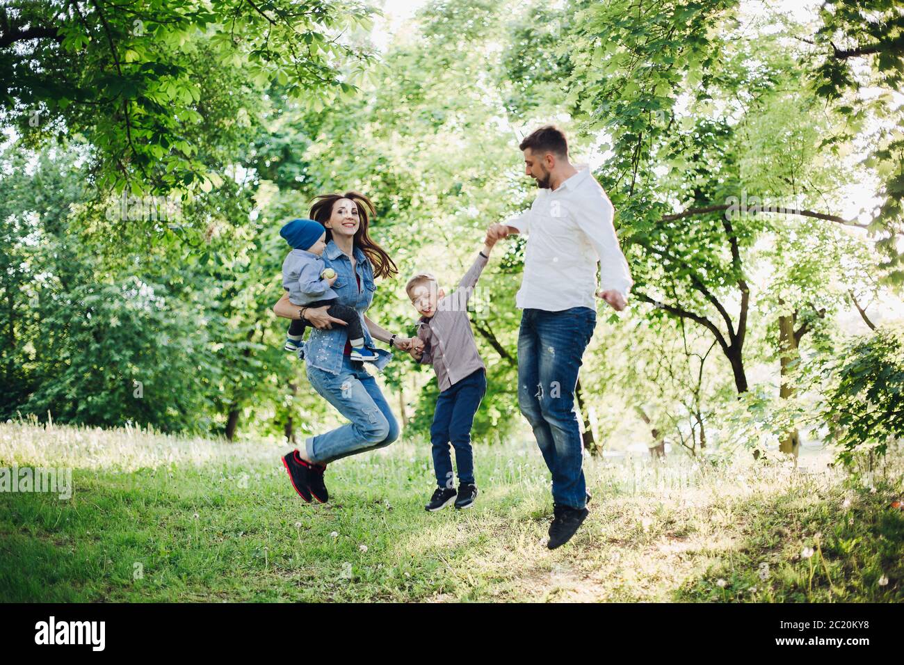 Active and positive family having fun and jumping in park together. Stock Photo