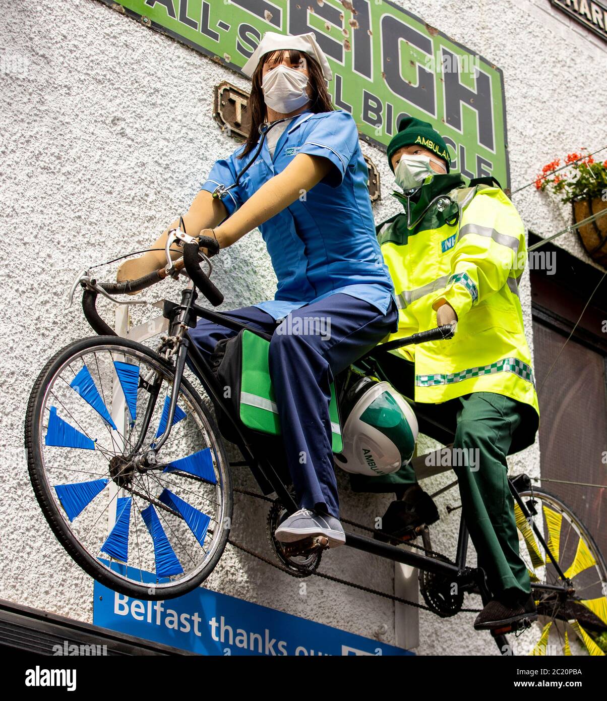 Two mannequins dressed as a nurse and an ambulance worker on a tandem