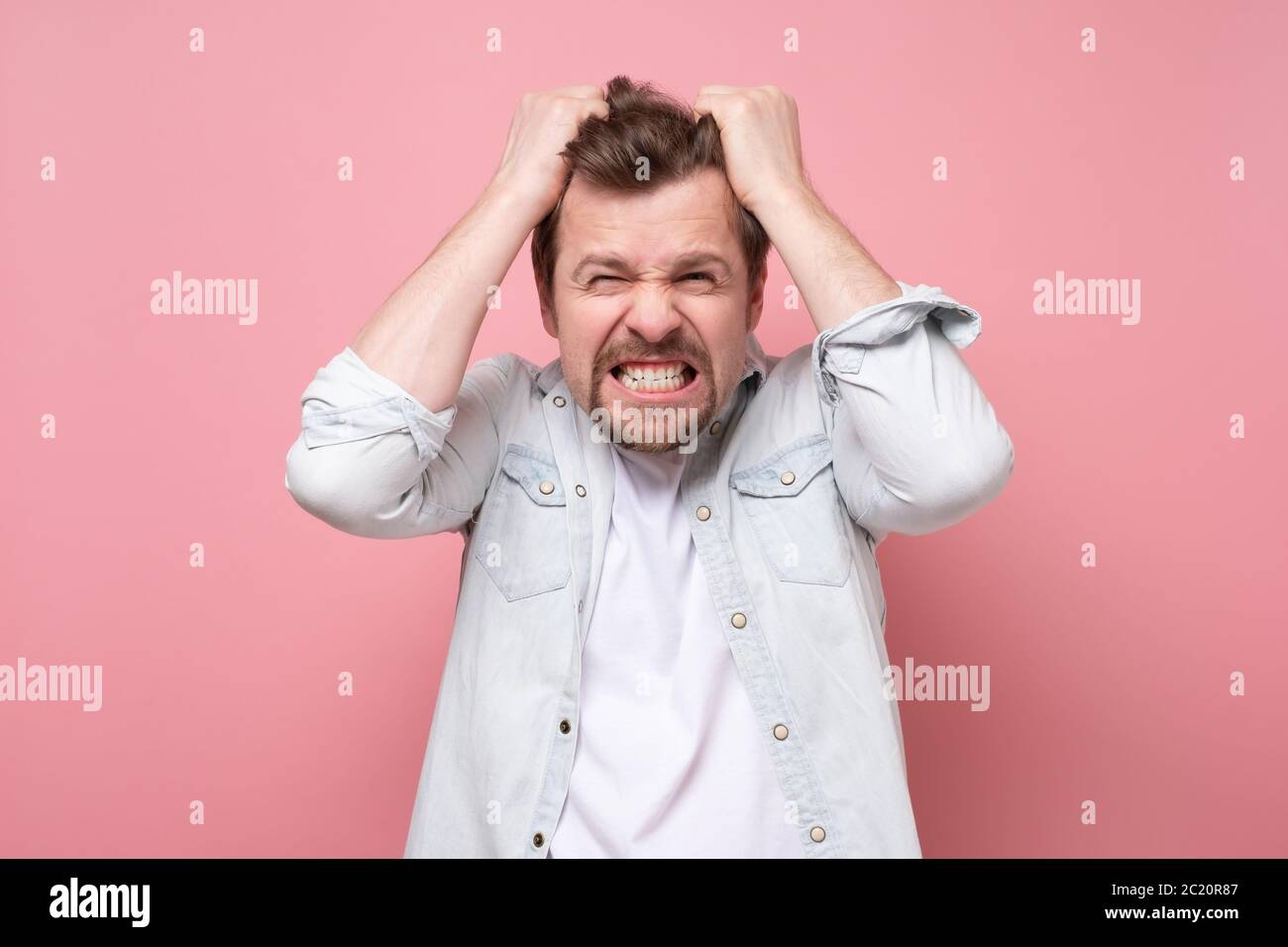 Young man in shock holding hands on head. Stock Photo