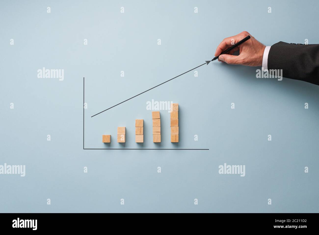 Hand of a businessman drawing a growing arrow above a column chart made ...