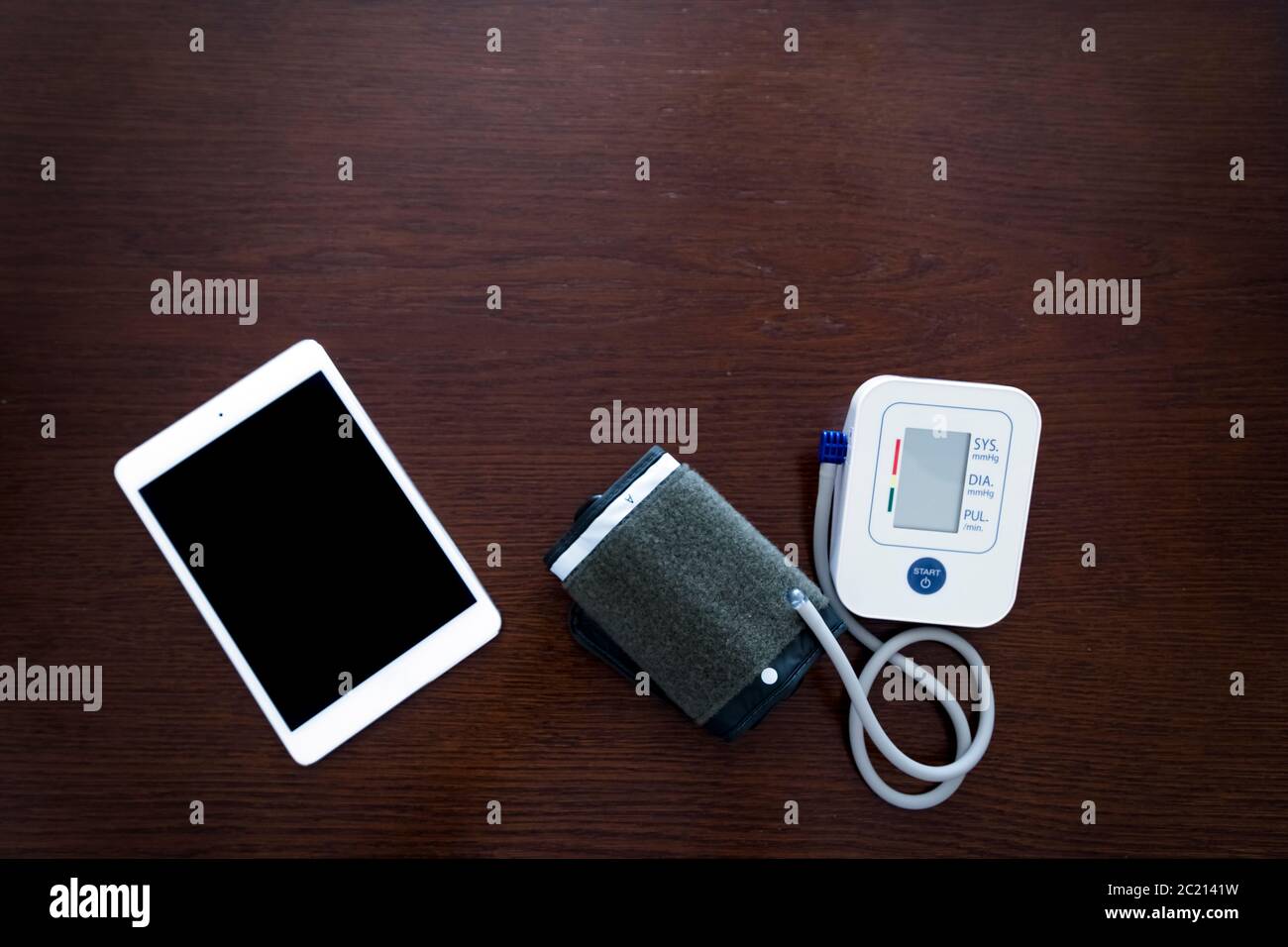 Digital blood pressure monitor with tablet on wooden table Stock Photo