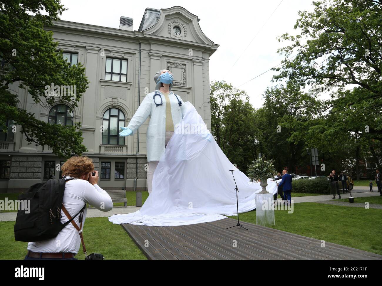 Riga, Latvia. 15th Jan, 2012. A woman photographs the statue 'Doctors for the World' by sculptor A. Bikse in front of the Latvian National Art Museum as a token of gratitude and appreciation for the selfless efforts of doctors and nurses during the Corona pandemic. It shows a doctor wearing a mouthguard and gloves, who has left the treatment room and stretches with her eyes closed to prepare for her next task. Credit: Alexander Welscher/dpa/Alamy Live News Stock Photo