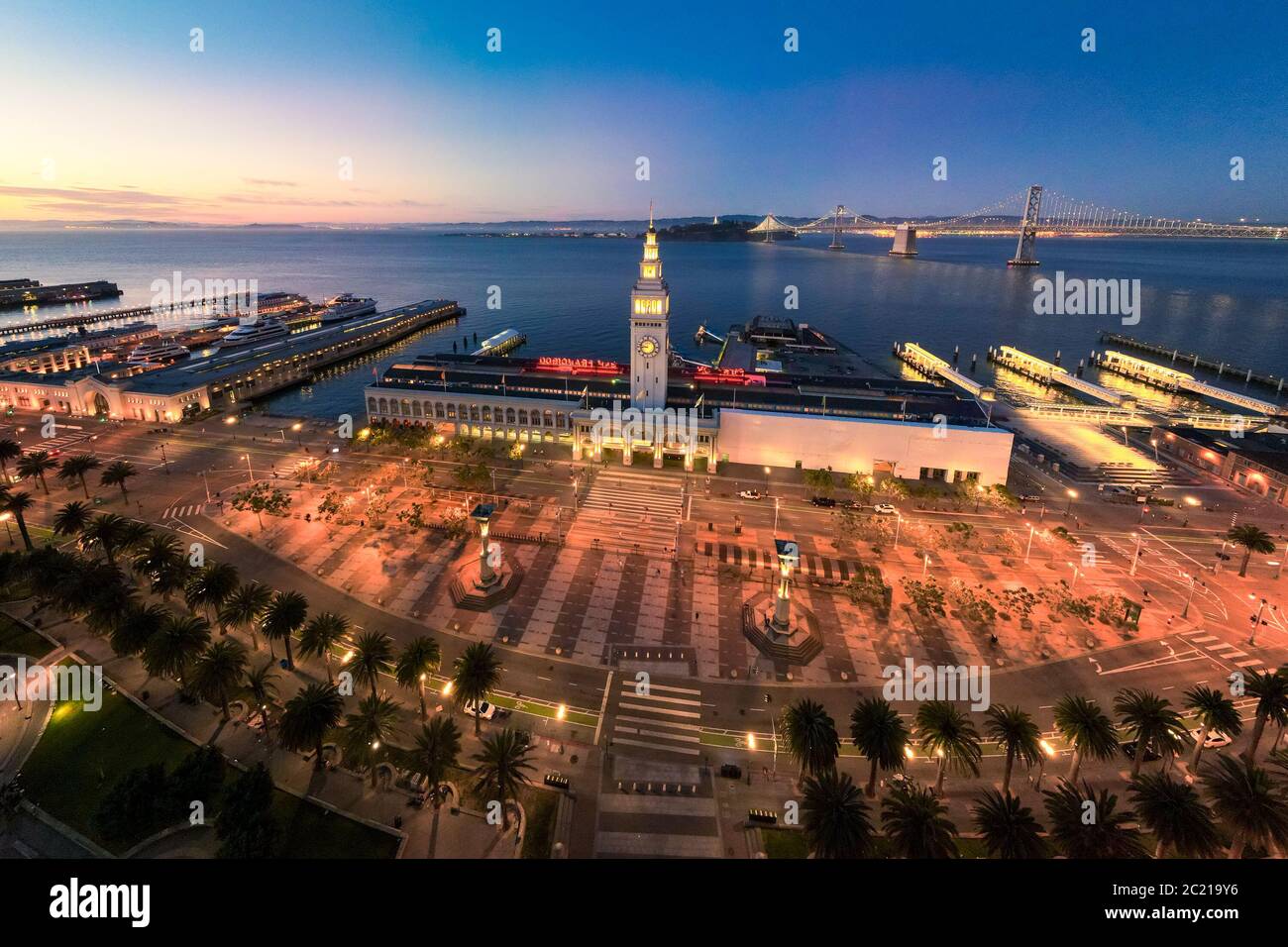 Aerial view of San Francisco Ferry Building and Justin Herman Plaza illuminated at night. Empty during shelter in place due to coronavirus. California Stock Photo