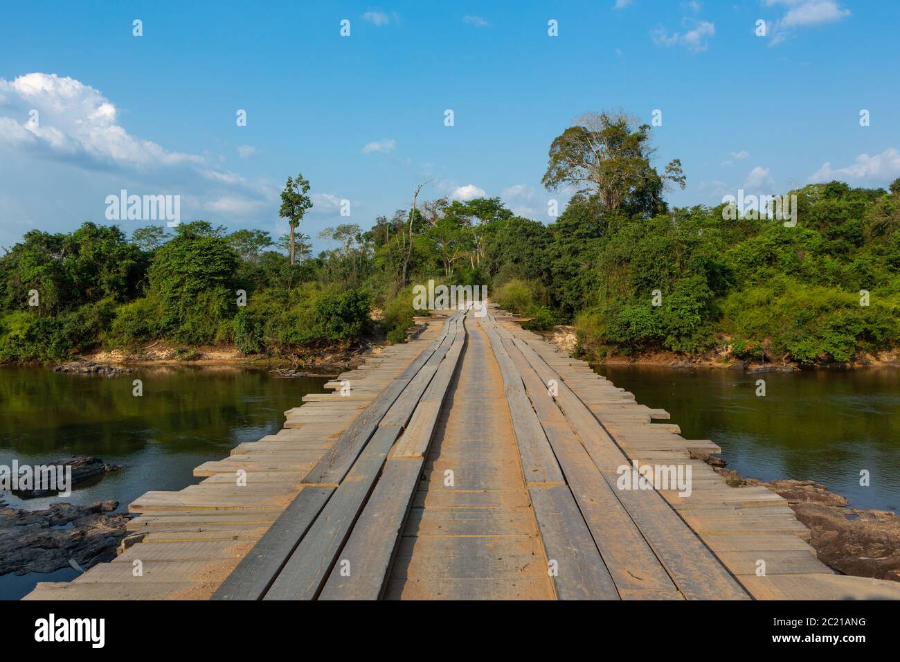 dangerous dirt road crossing wooden rustic bridge over river in the