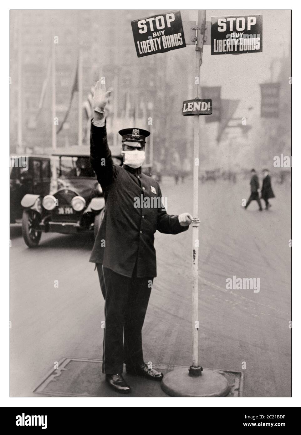 Spanish Flu 1918 mask American Traffic Policeman in New York City wearing an anti flu gauze mask. 1918 spanish flu pandemic, with World War 1 sign above urging purchase of Liberty Bonds New York USA Stock Photo