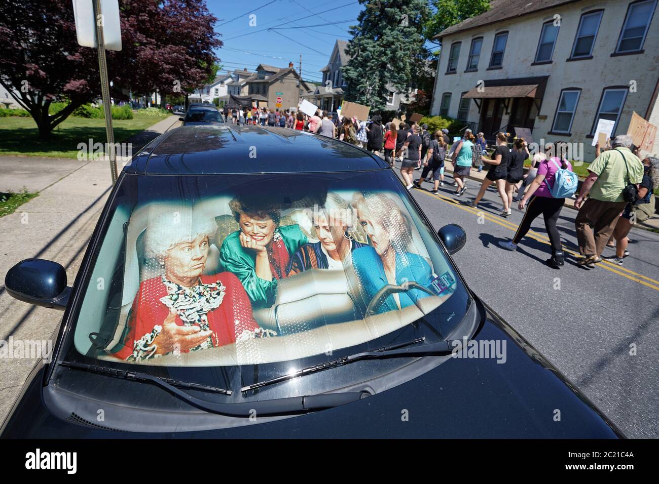 Community members walk past a car with a 'Golden Girls' themed sun shield in a car June 14, 2020, during a peace march in Emmaus, Pennsylvania. Stock Photo