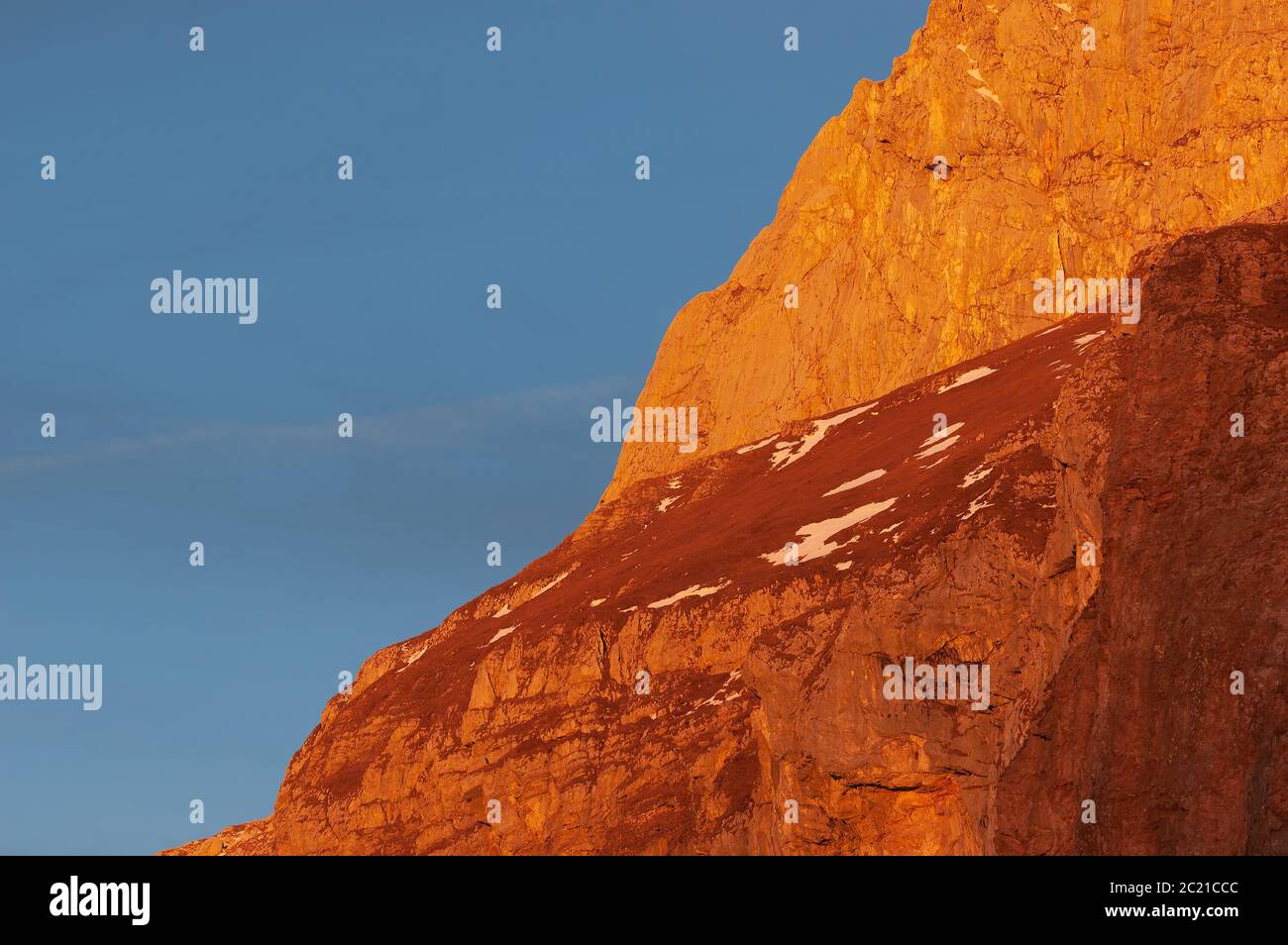Evening view of vibrantly red sunlit mountainside of Mangart mountain in Julian Alps in Slovenia. Alpinism, travel, mountaineering and tourism concept Stock Photo