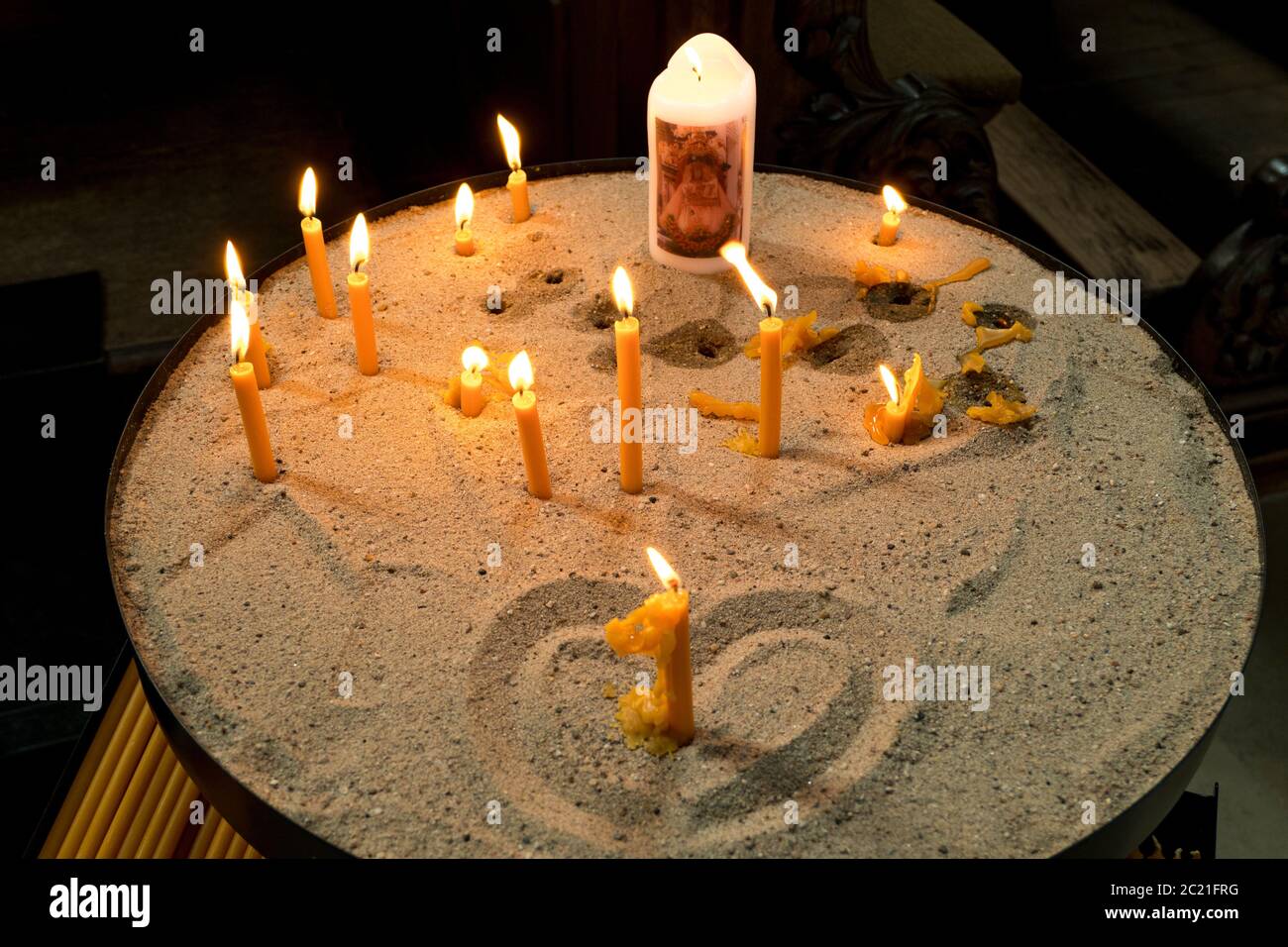 Candles burning in the church on sand with heart Stock Photo