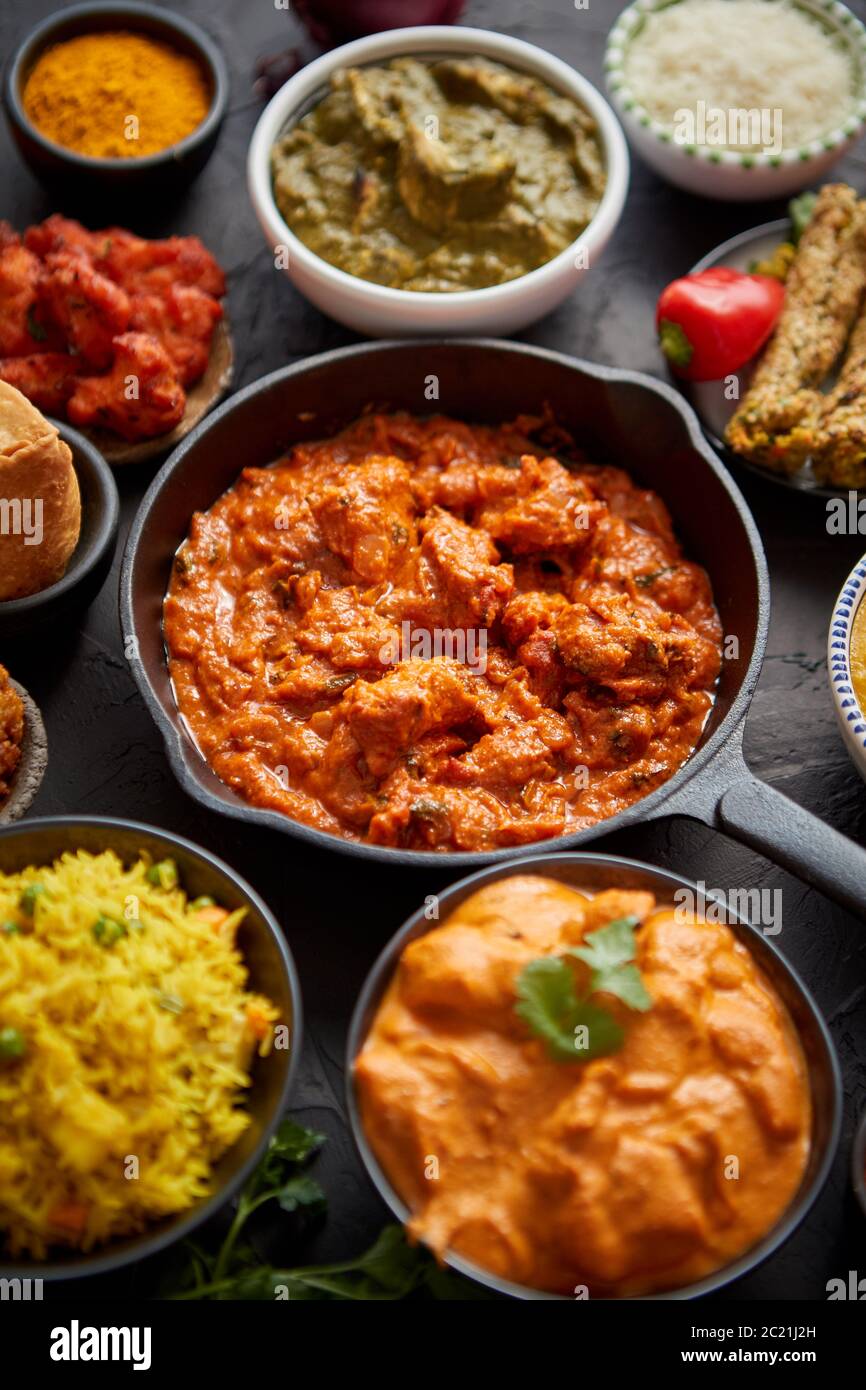 Various Indian dishes on a table. Spicy chicken Tikka Masala in iron