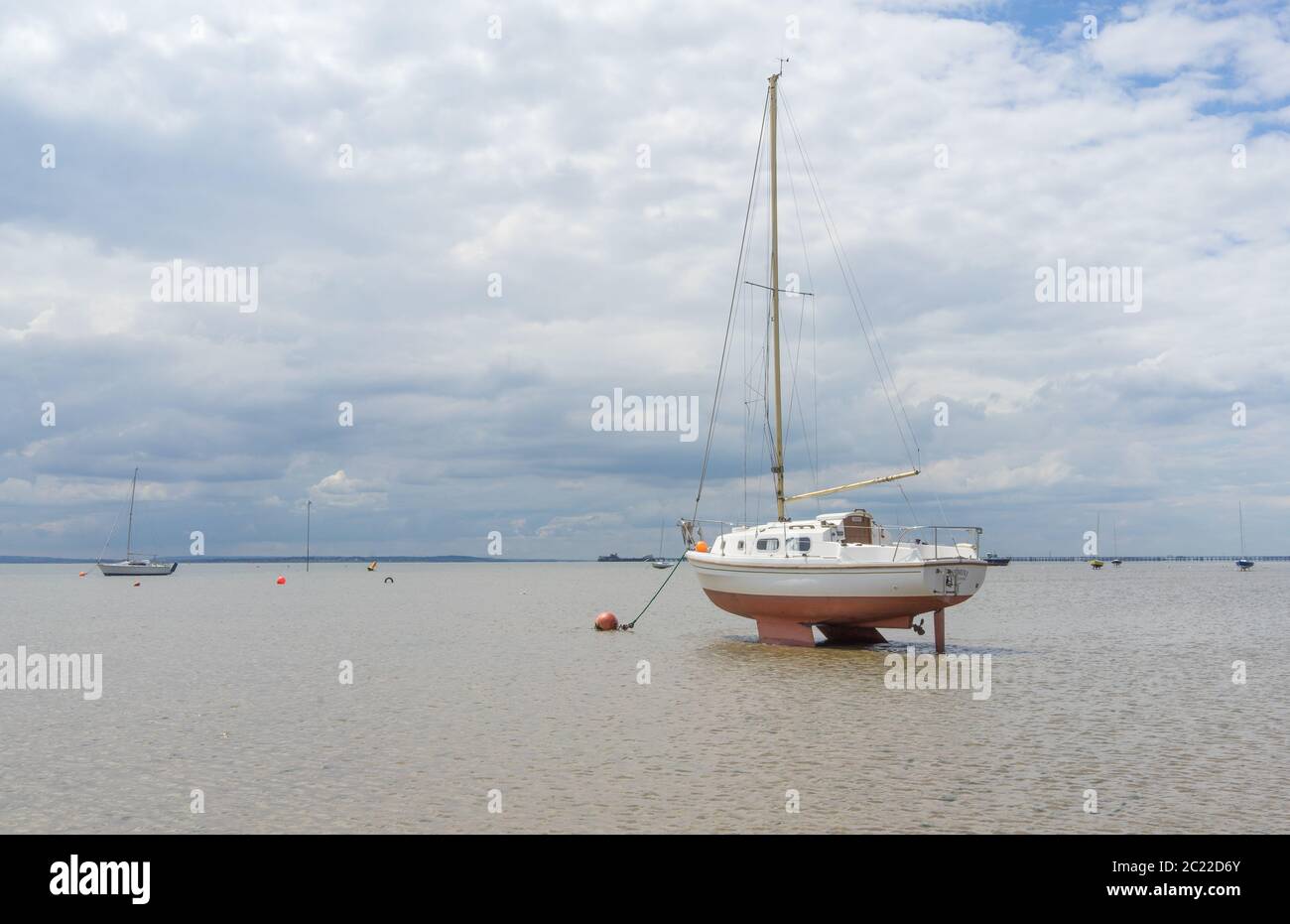 Boat in very shallow water tied up on the beach during low tide. Shoeburyness, Southend on Sea, Essex Stock Photo