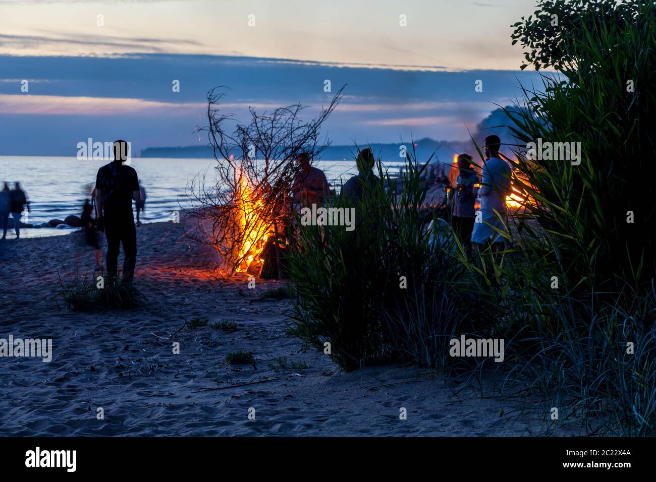 Unrecognisable people celebrating summer solstice with bonfires on beach Stock Photo