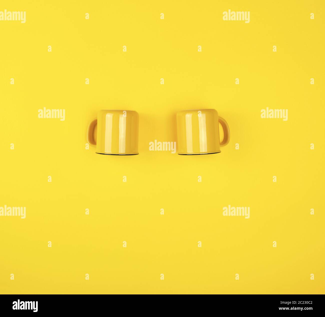 two yellow ceramic cups with a handle on a yellow  background, flat lay, copy space Stock Photo