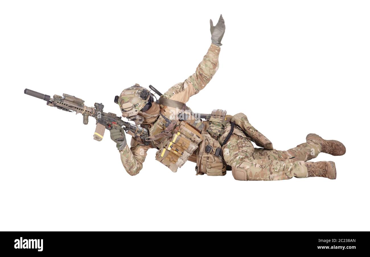 Modern army soldier, infantry rifleman equipped with tactical ammunition and radio, lying on ground, observing territory trough optical sight, aiming, Stock Photo