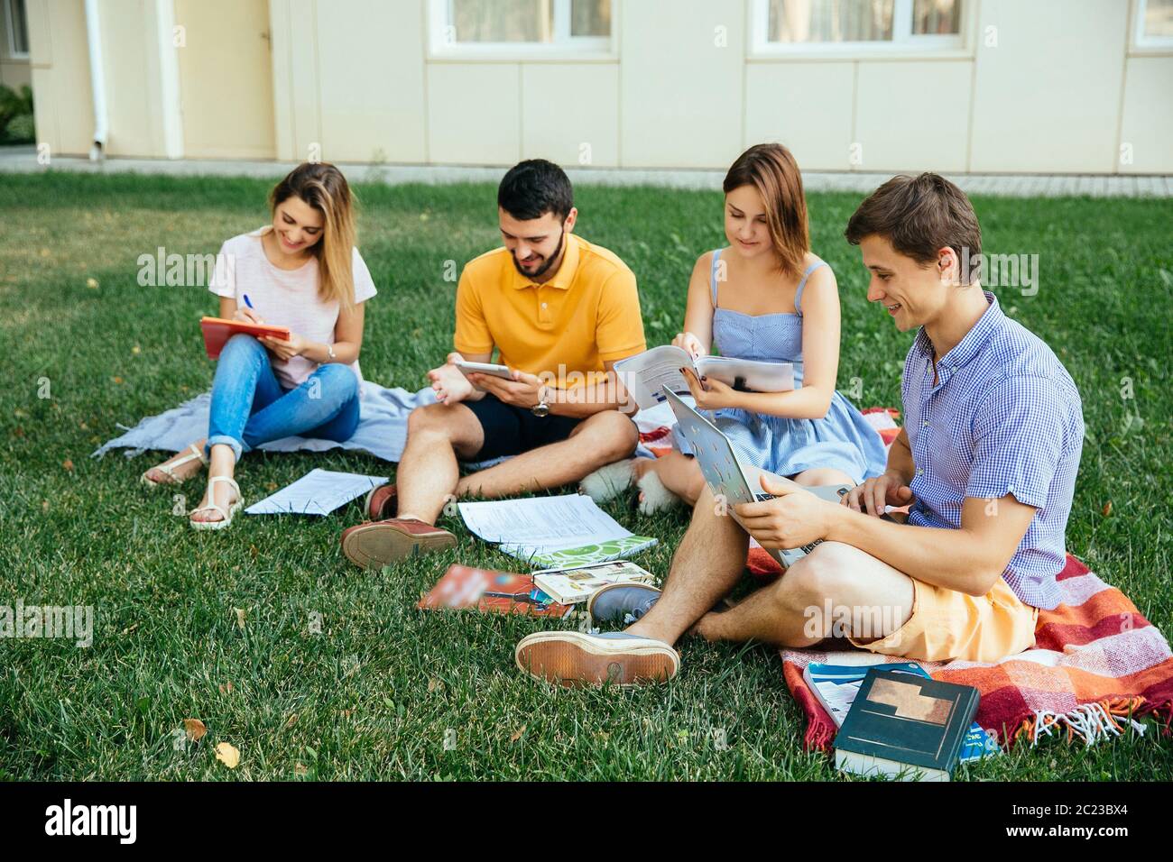Group of studying students sitting on grass with note books Stock Photo