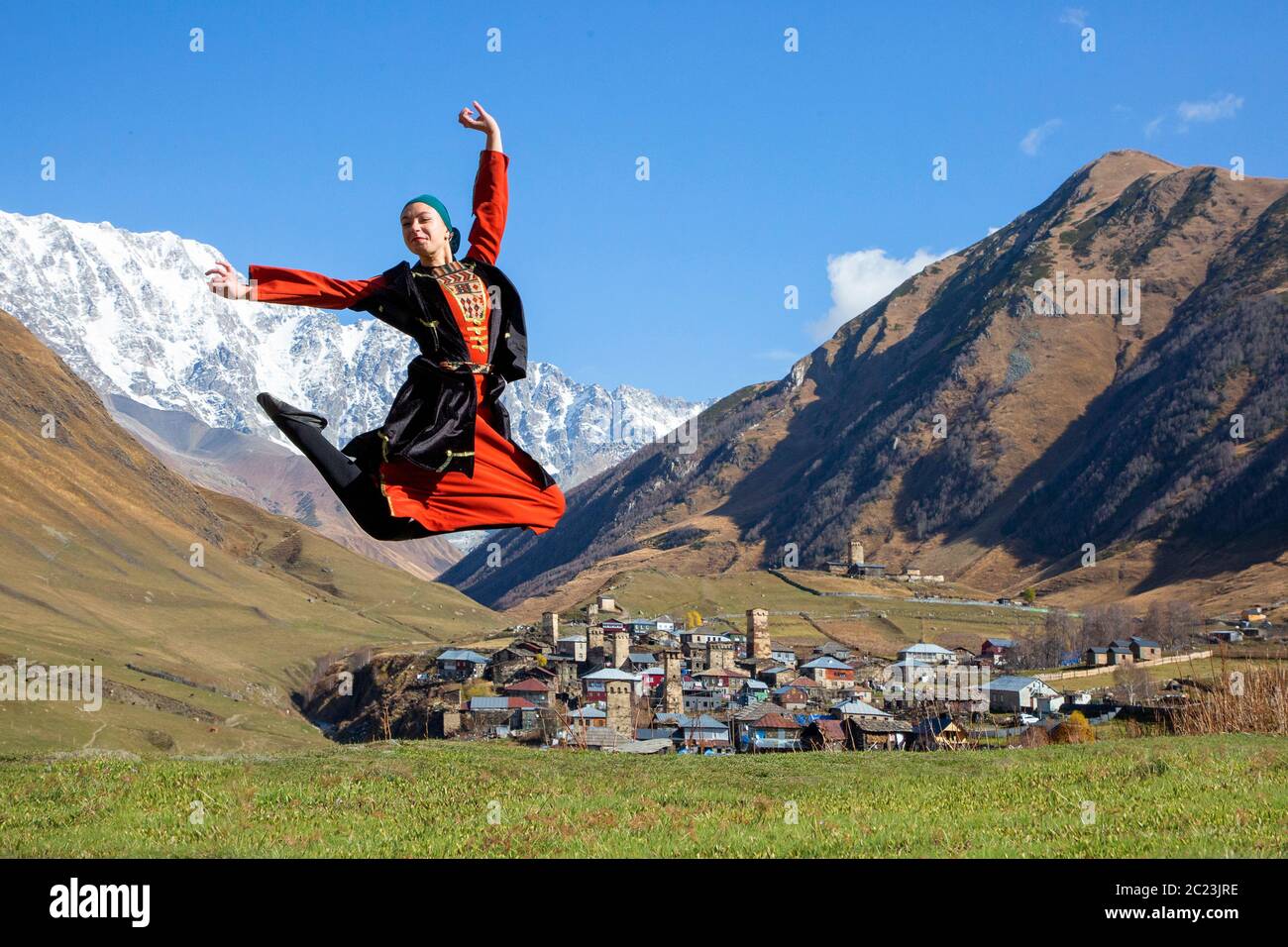 Georgian woman in local Svaneti costumes performing traditional dance, with mount Shkhara in the background, in Ushguli, Georgia Stock Photo