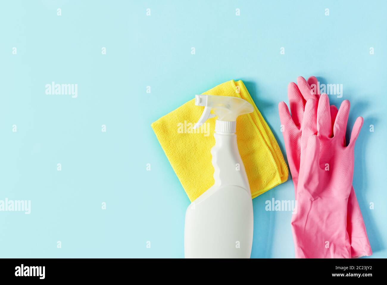 Bottle of detergent, microfiber rag and protective gloves on pastel ...