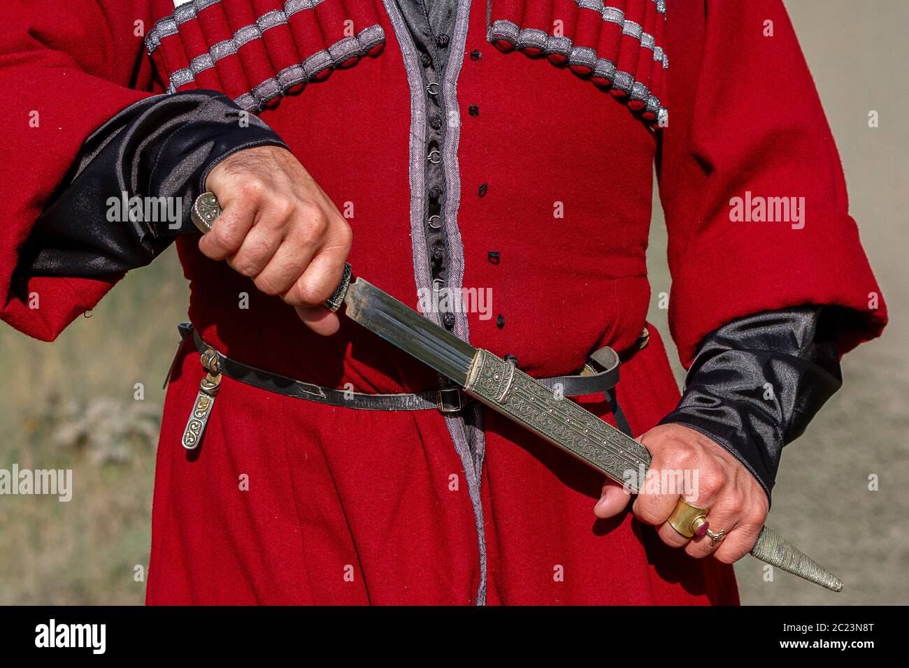 Georgian man in traditional clothes pulling the dagger, Caucasus Mountains, Georgia Stock Photo