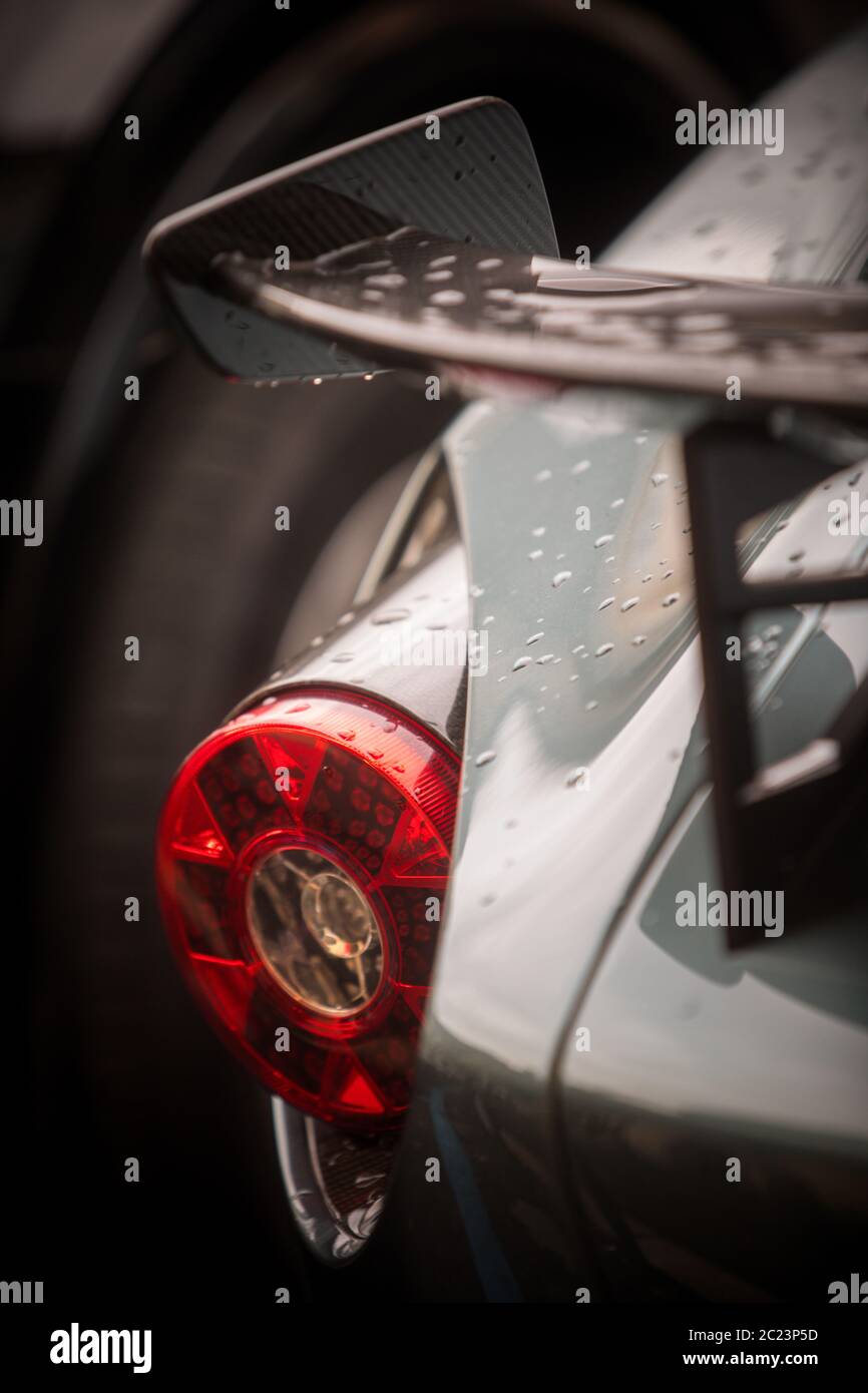 Color close up of a sport car's rear brake light and spoiler with rain drops. Stock Photo