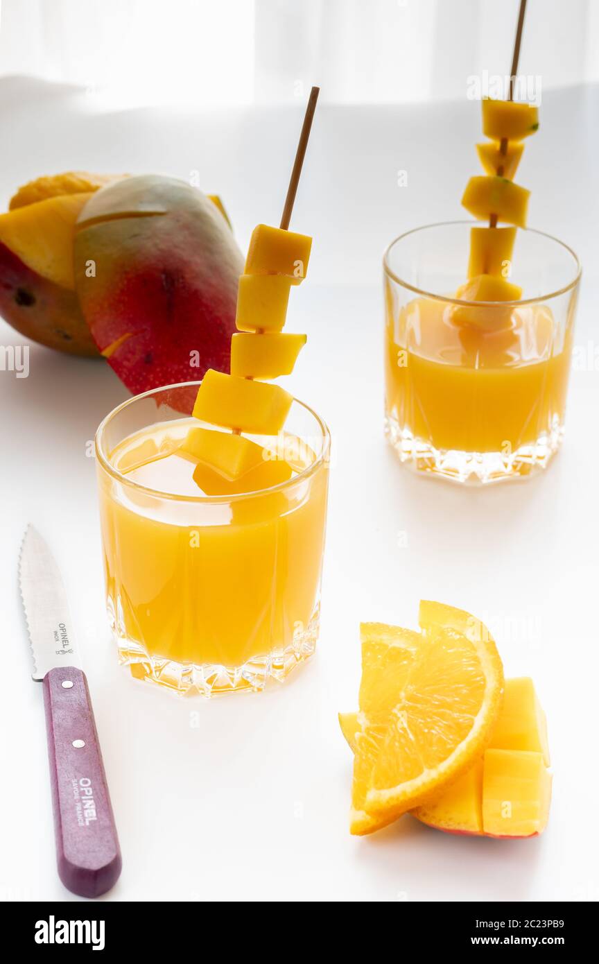 Mango juice with orange. Kitchen knife and chopped fruits. High key