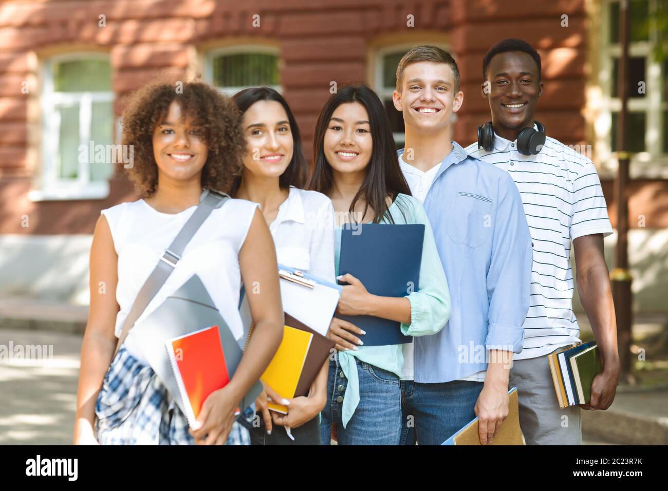 Group of smiling multicultural students posing near university campus ...