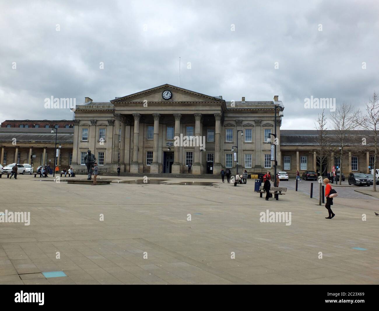Huddersfield, West Yorkshire, England - April 26, 2018: Pedestrians in St Georges Square walk past the historic railway station Stock Photo