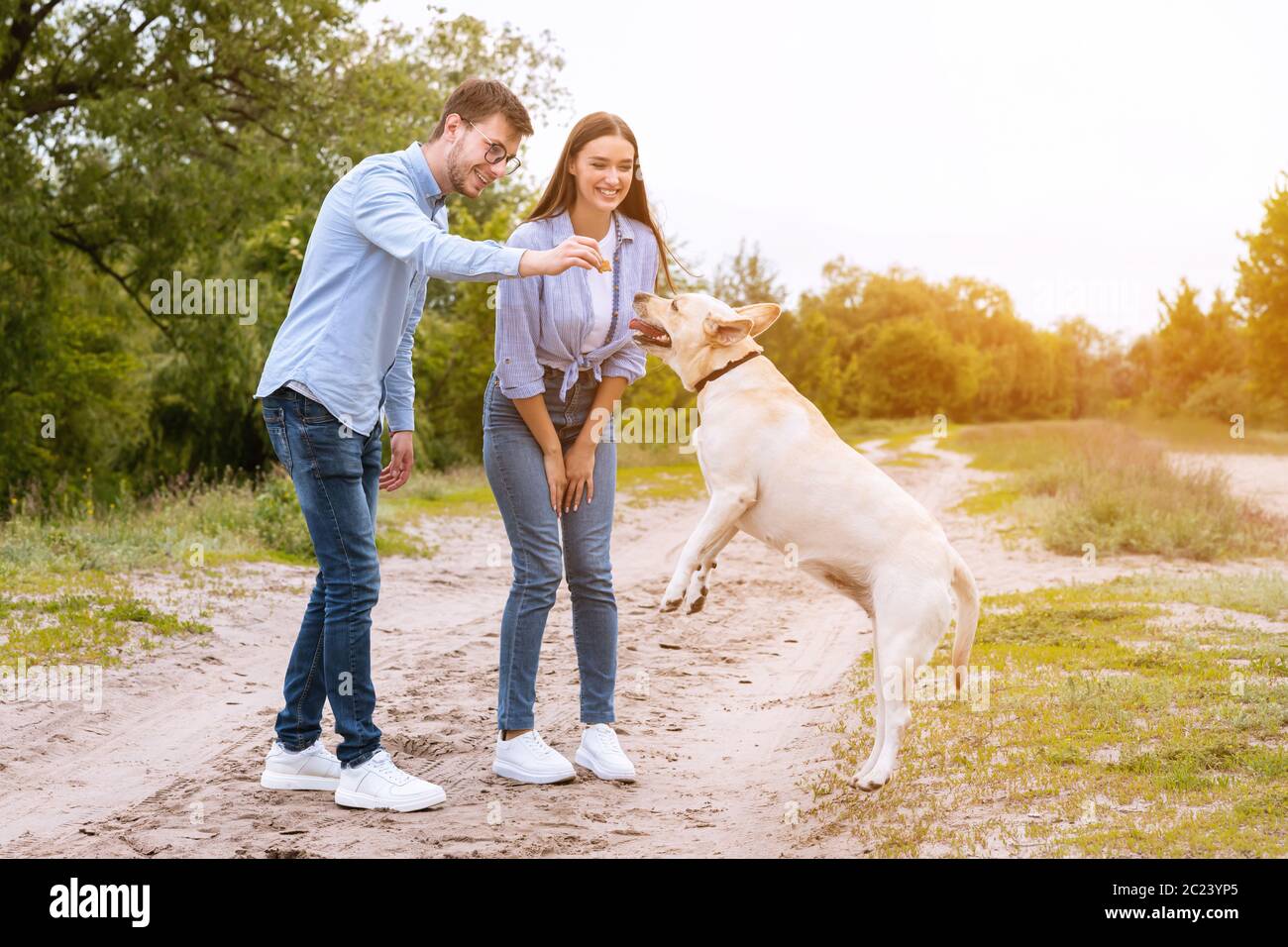 Young couple giving a treat to their happy dog Stock Photo