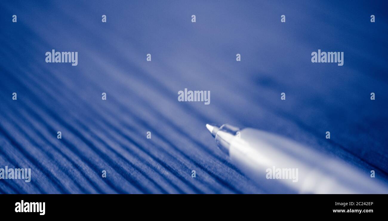 Ball pen on the blue wooden table. Macro photo, side view. Stock Photo