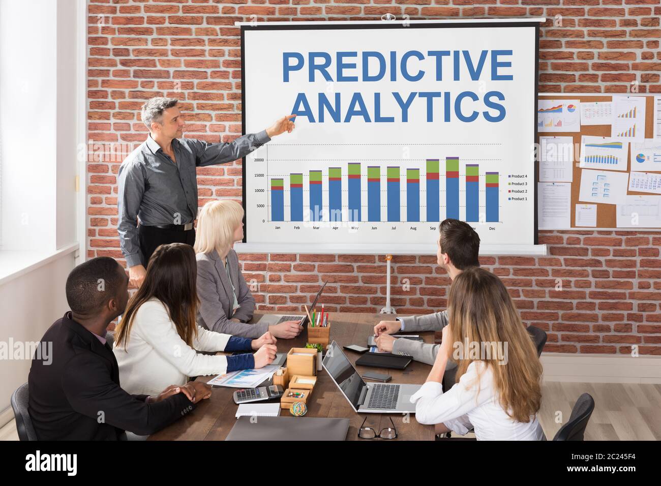 Businessman Giving Predictive Analytics Presentation To His Colleagues In Office Stock Photo