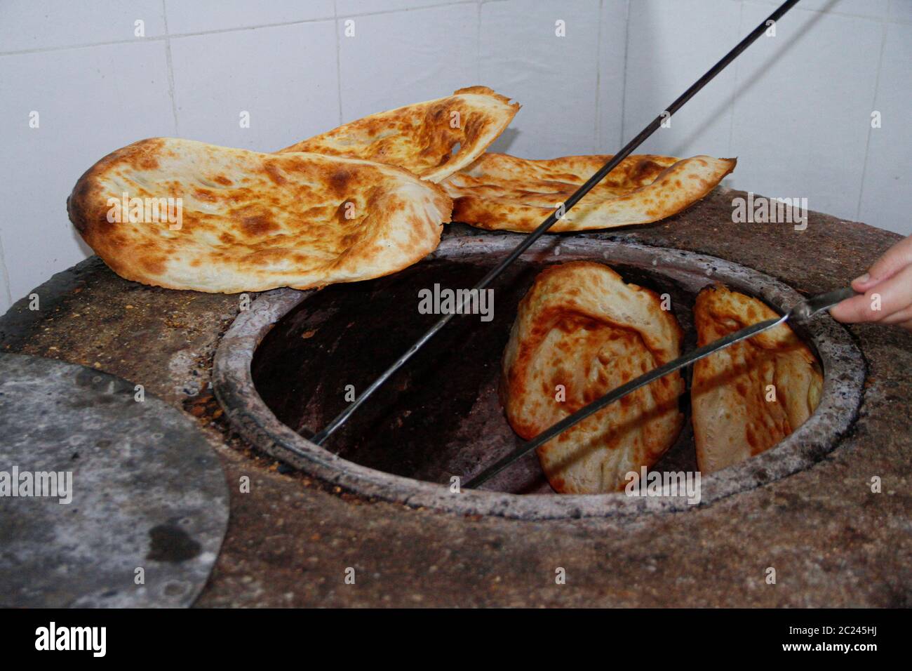 Traditional caucasian tandir bread cooking and putting aside Stock Photo