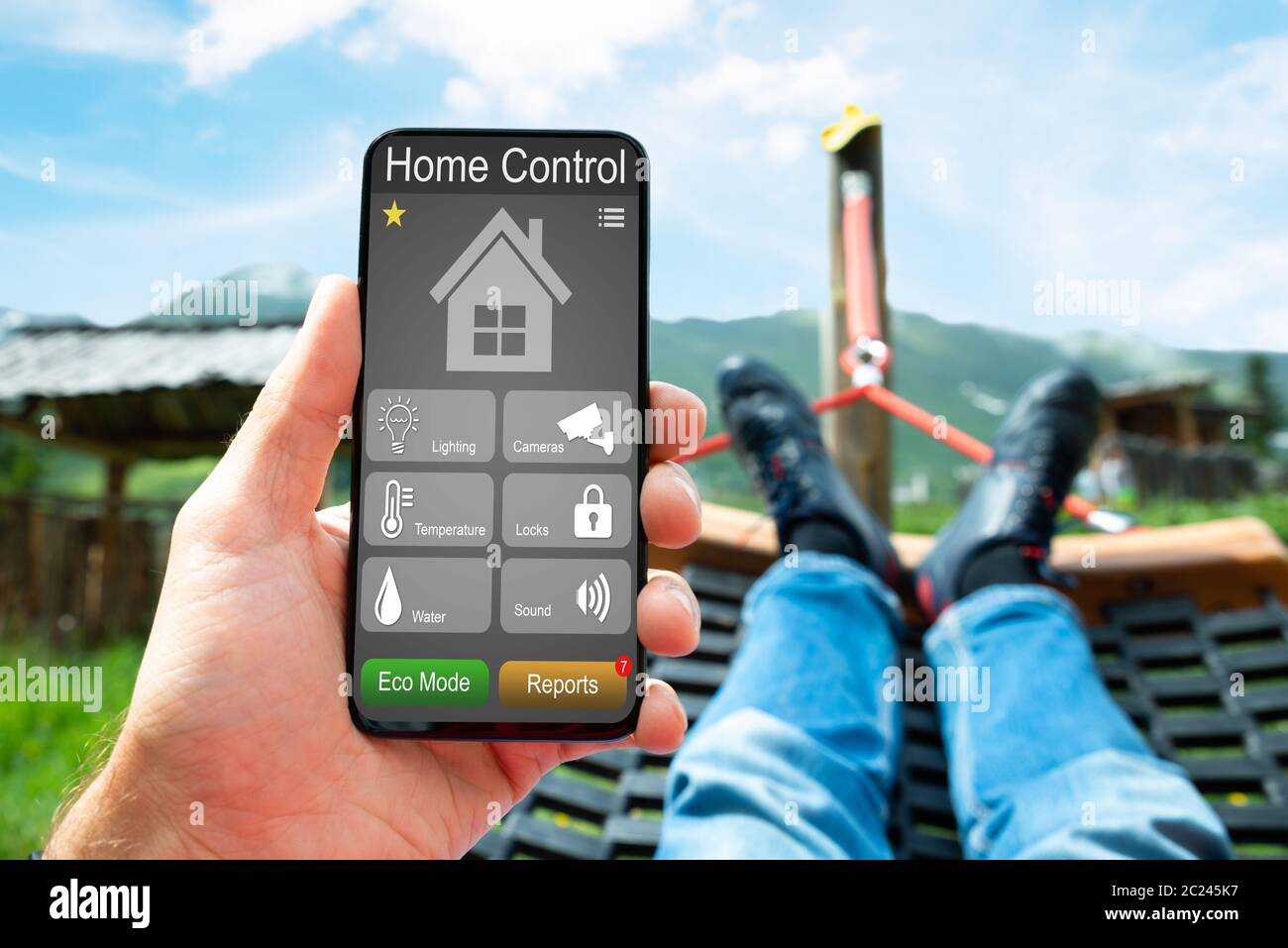 Man Lying In Hammock Using Smart Home And Security System App Stock Photo