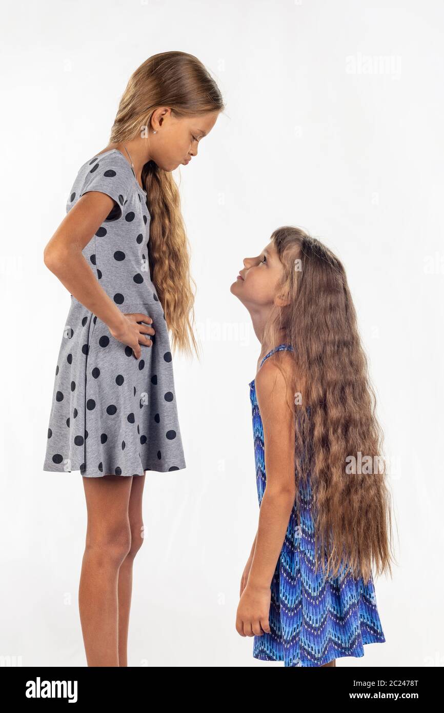 Two girls of different stature, one stood on a chair and became even taller Stock Photo