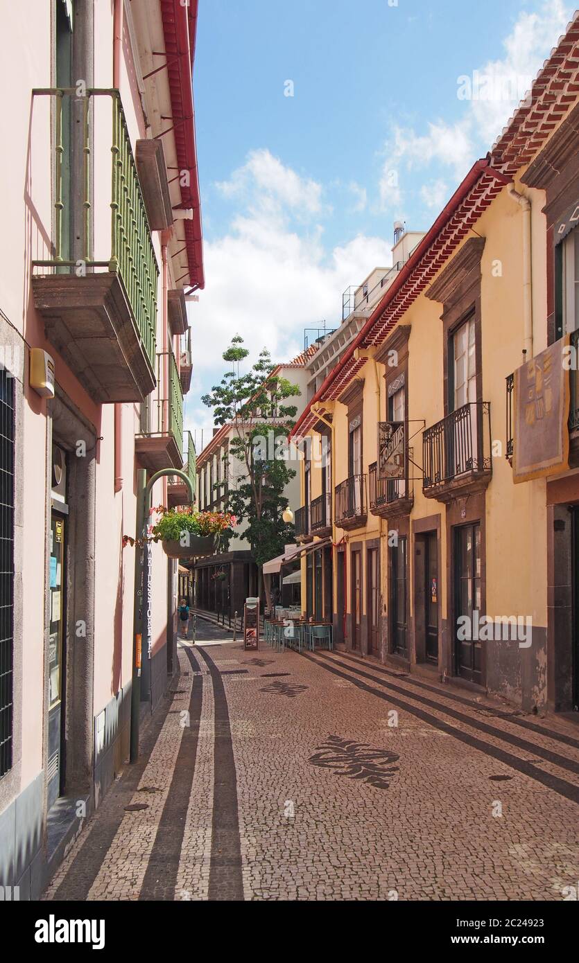 a quiet cobbled street in funchal madeira with a traditional style hotel and cafe with balconies and painted houses Stock Photo