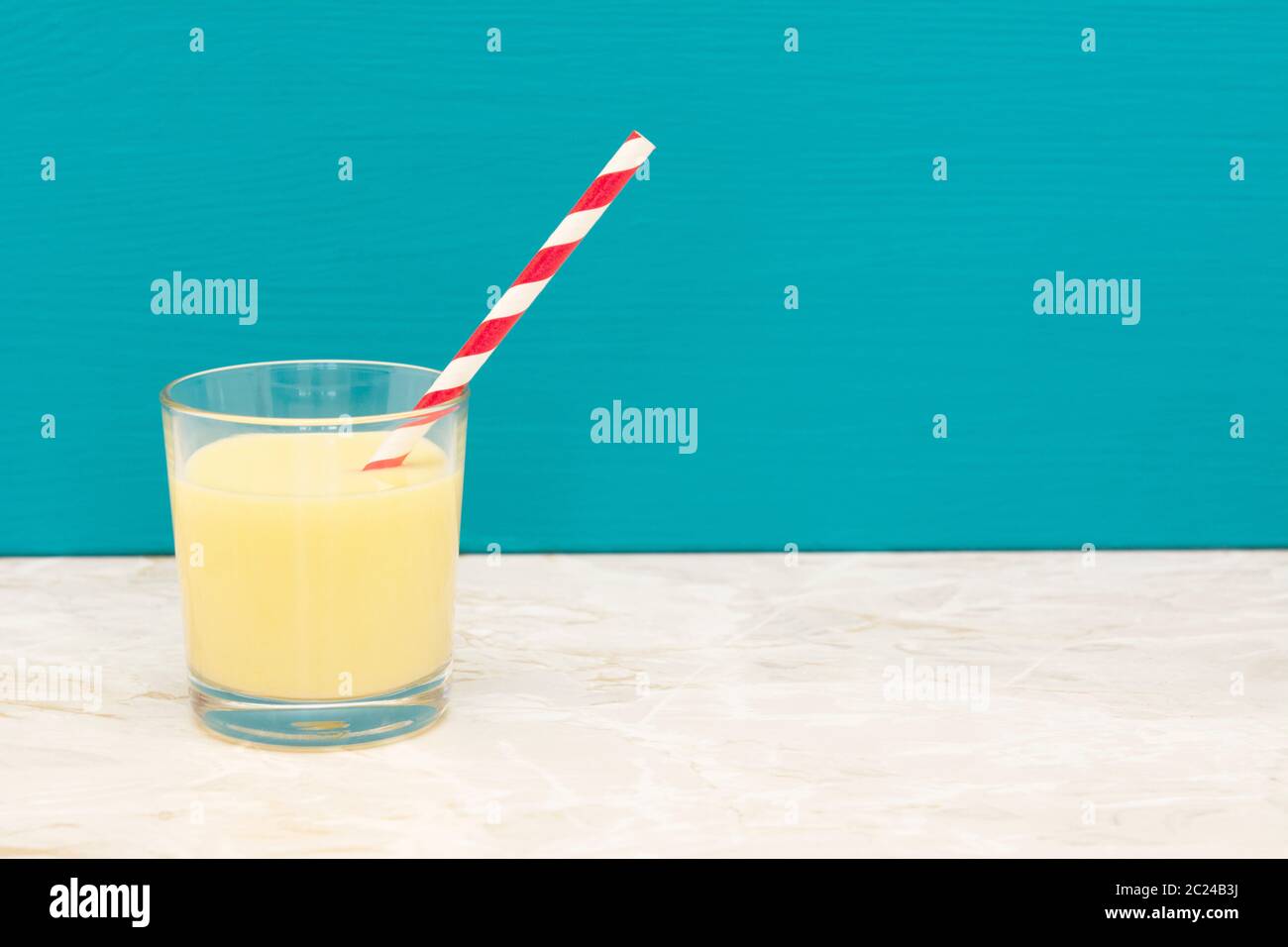 https://c8.alamy.com/comp/2C24B3J/tasty-banana-milkshake-with-a-retro-paper-straw-in-a-glass-tumbler-with-a-teal-background-and-copy-space-2C24B3J.jpg