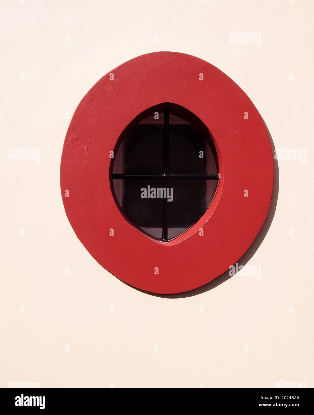 bright red stone oval window frame in a white wall with black metal ...