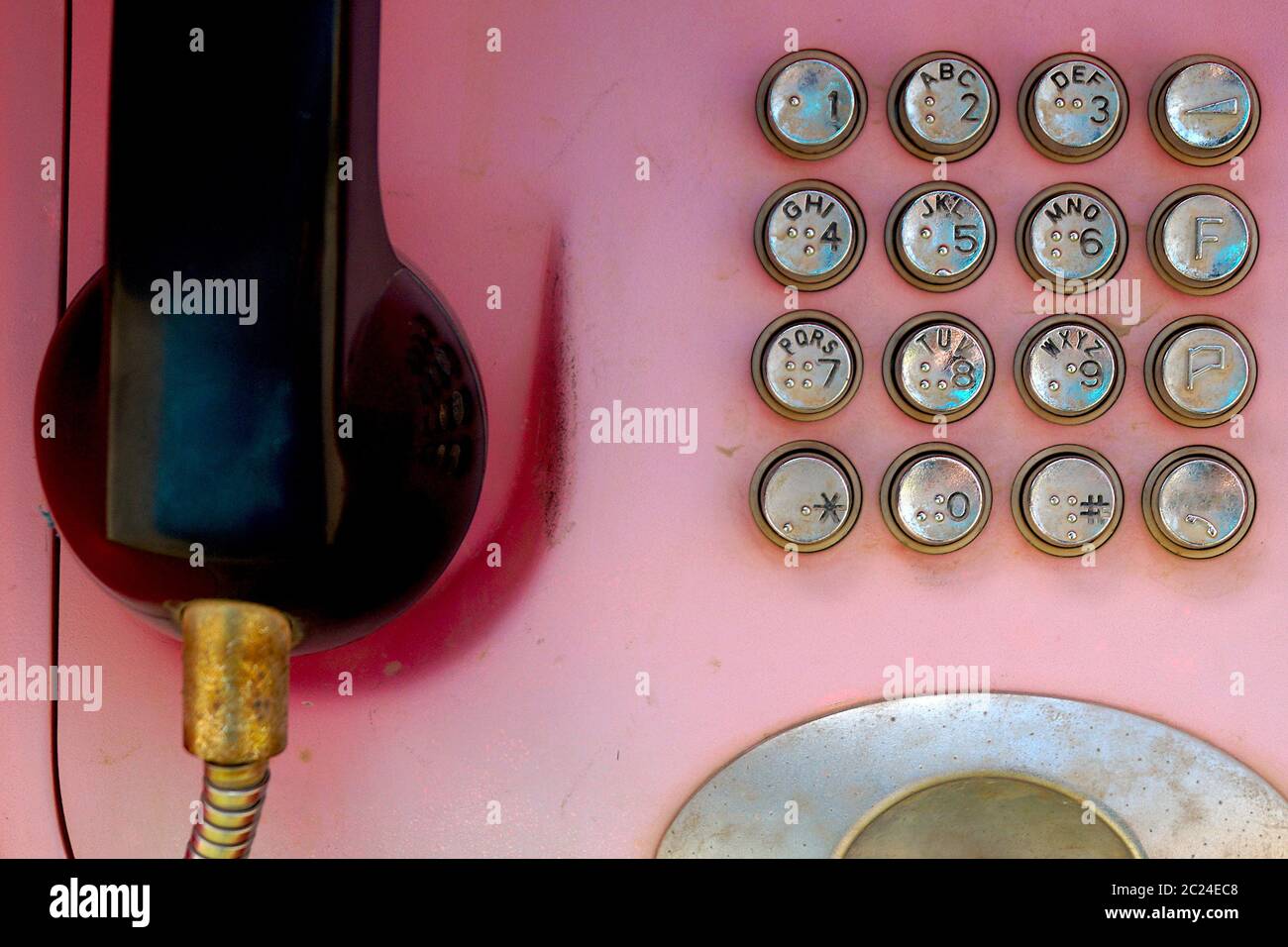 Old faded red telephone with metal buttons. Stock Photo
