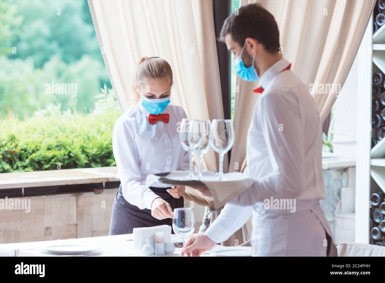 the waiter serves a table in a cafe in a protective mask Stock Photo ...