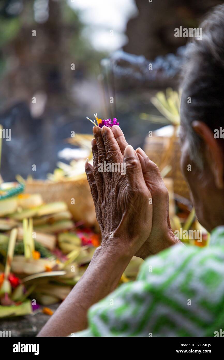Old woman folds hands to prayer with prey in Hindu temple Bali Stock Photo