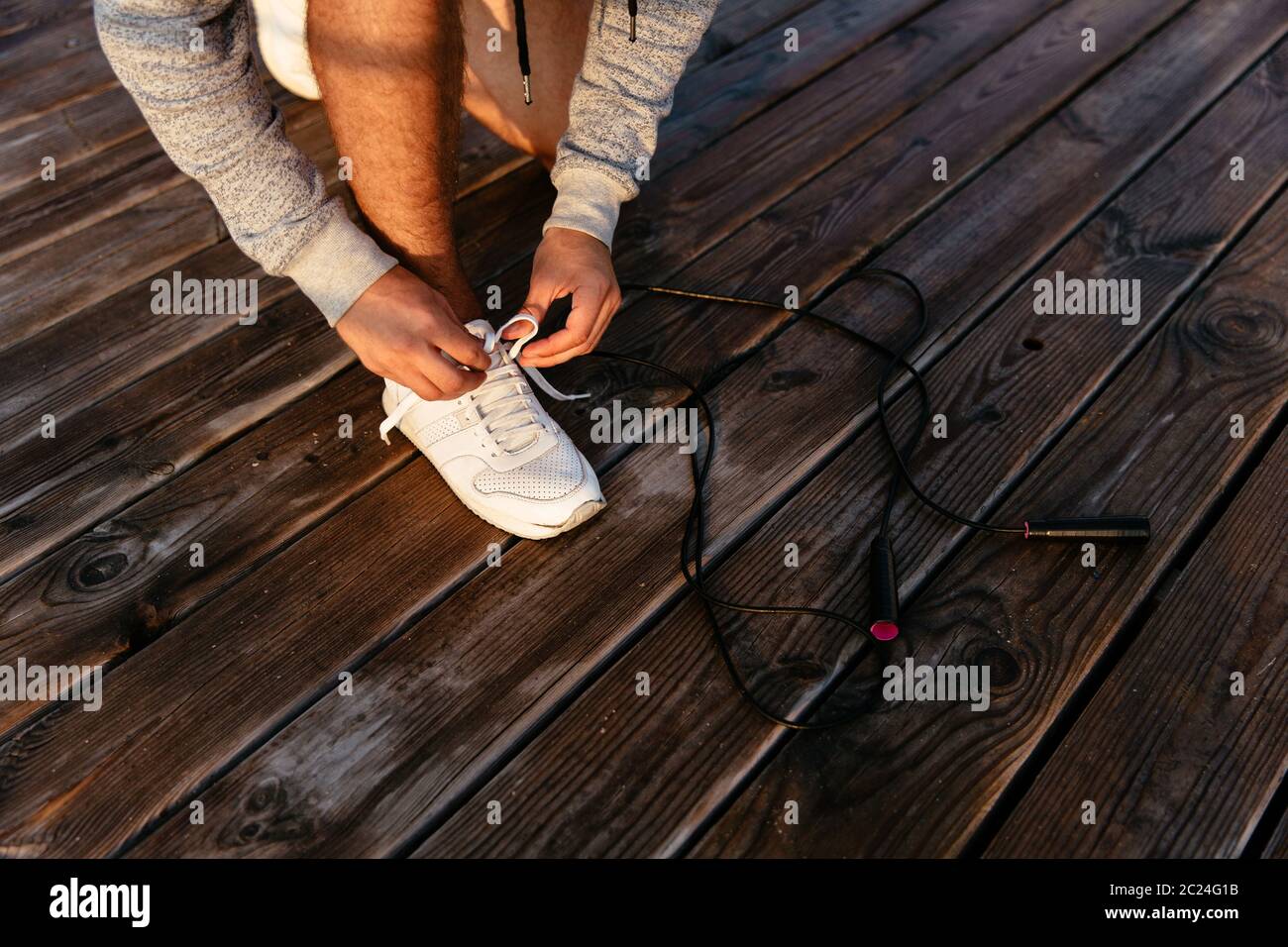 View of Close-up photo of young sportsman in sportswear tying shoelace, before ...