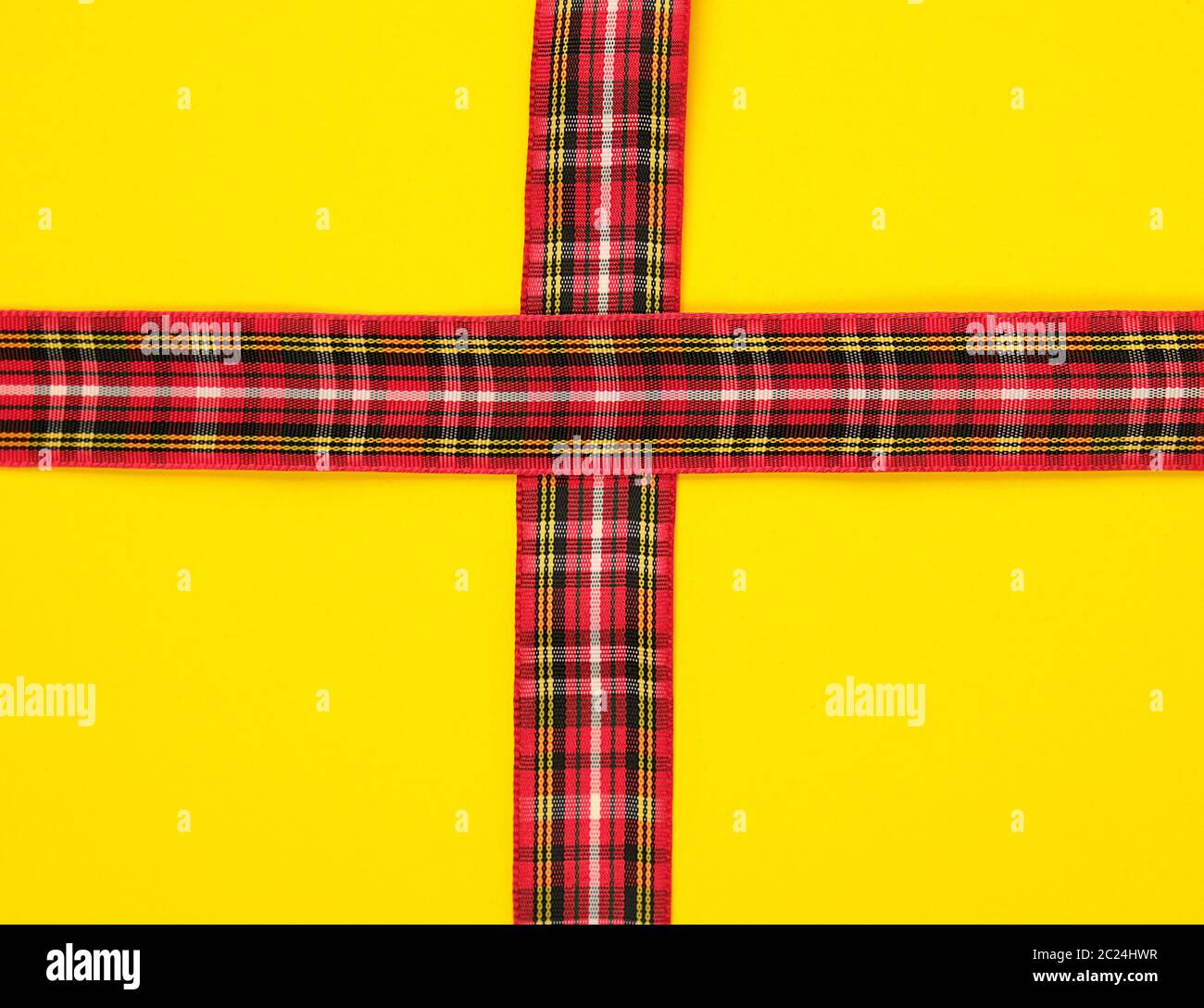 red decorative ribbon in a box cross on a cross on a yellow background