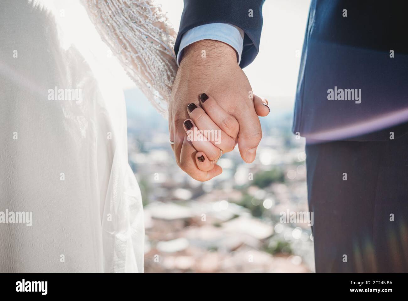 Wedding couple holding hands close up on beautiful day with city in background Stock Photo