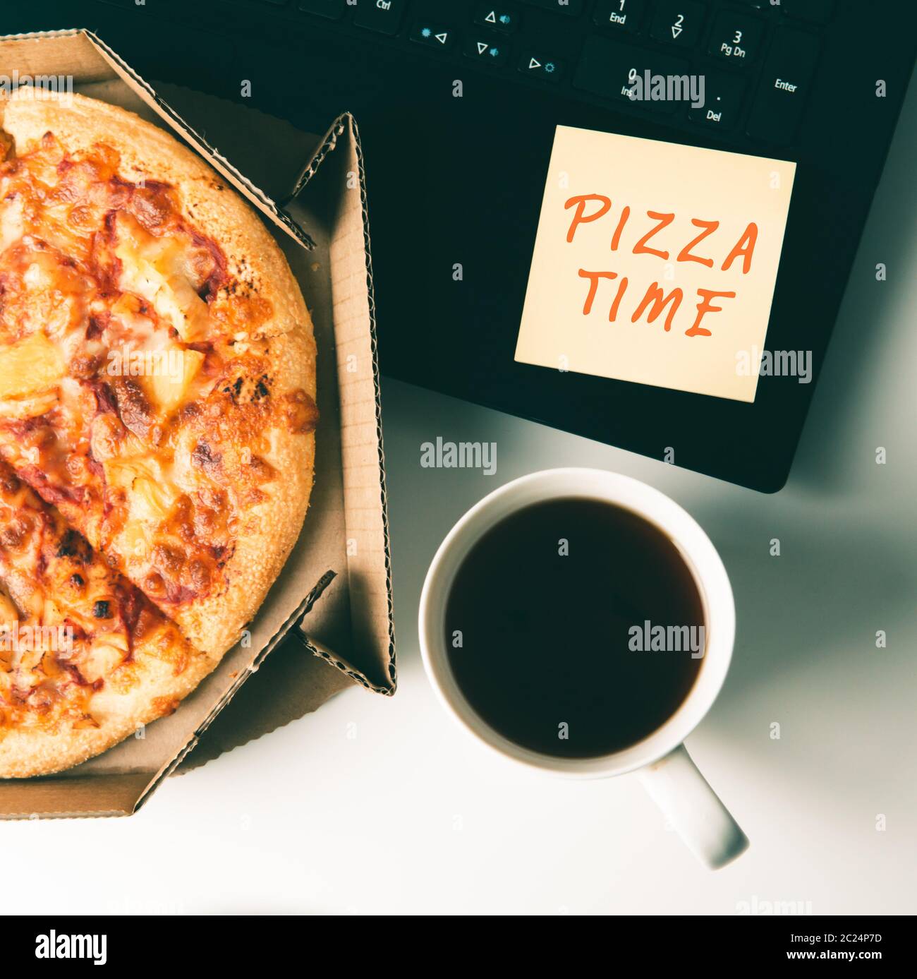 Pizza in box, cup of coffee, laptop and sticker with text PIZZA TIME on desk in office. Concept of food or pizza delivery and break on working day. Stock Photo